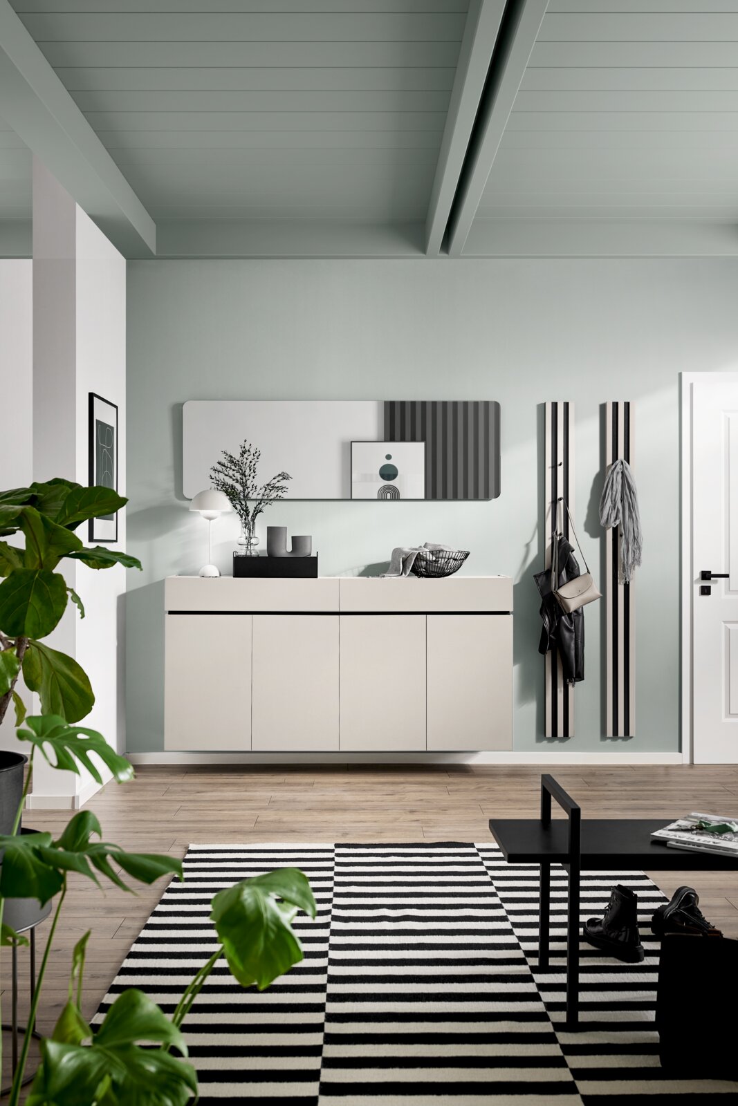 Moderner XXL-Schuhschrank in einem stilvollen Flur, frontal betrachtet, mit Dekorationen und einem großen Spiegel darüber.