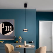 Moderne schwarze Pendelleuchte mit zylindrischer Deckenhalterung und flachem Schirm über einem Esstisch in blauem Esszimmer, Frontalansicht auf Augenhöhe