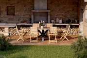 Houten tuinstoel in een gezellige terrasomgeving, van voren gefotografeerd, met een eettafel en andere stoelen.