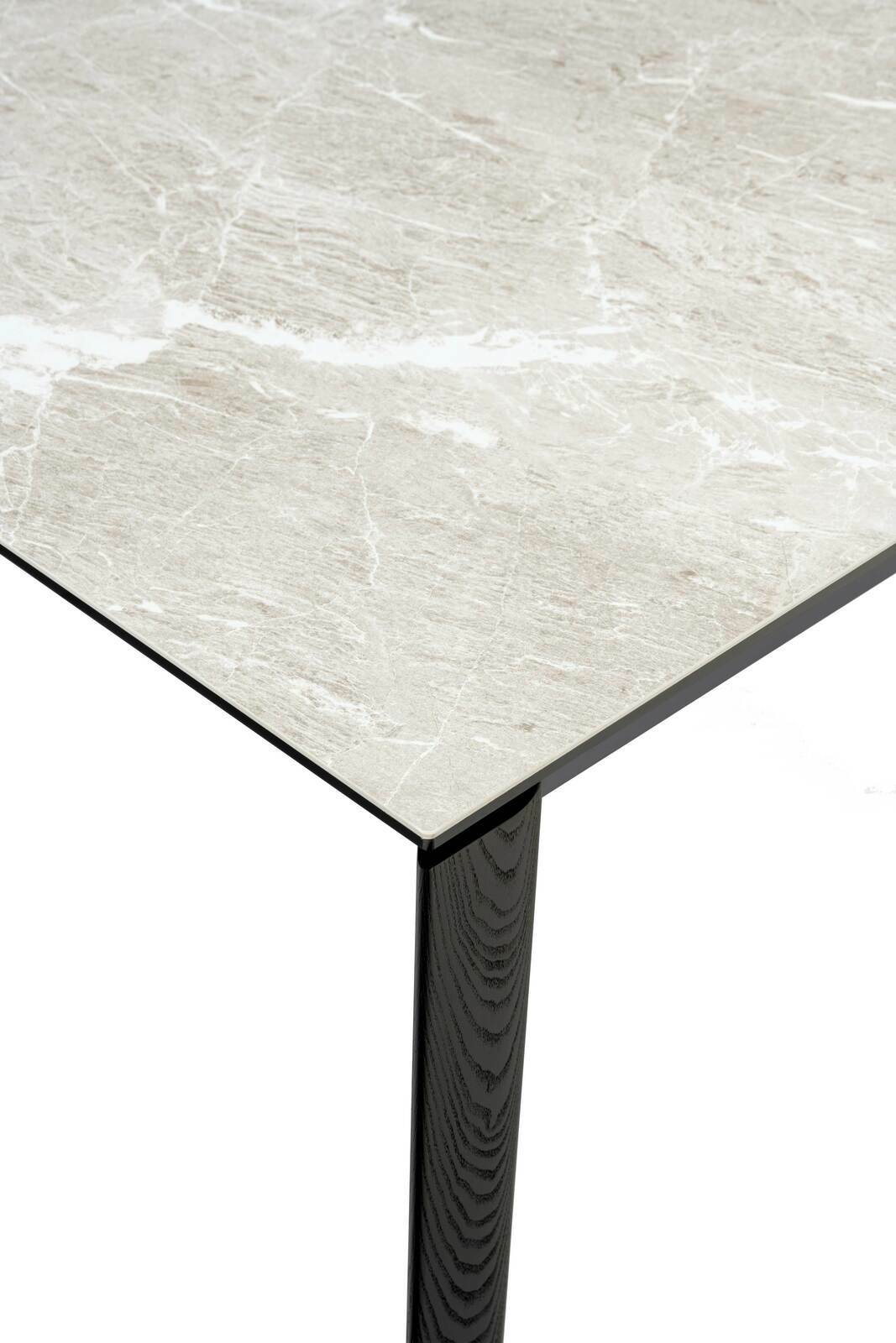 Nahaufnahme eines Esstisches mit einer hellen, marmorierten Tischplatte und einem dunklen, hölzernen Tischbein, aus der Perspektive von oben.