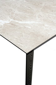 Nahaufnahme eines Esstisches mit einer hellen, marmorierten Tischplatte und einem dunklen, hölzernen Tischbein, aus der Perspektive von oben.