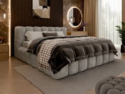 Polsterbettgestell in einem modernen Schlafzimmer, seitliche Perspektive, mit grauem, gestepptem Design und gemütlicher Bettwäsche.