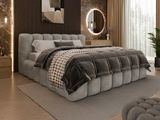 Polsterbettgestell in einem modernen Schlafzimmer, seitliche Perspektive, mit grauem, gestepptem Design und gemütlicher Bettwäsche.