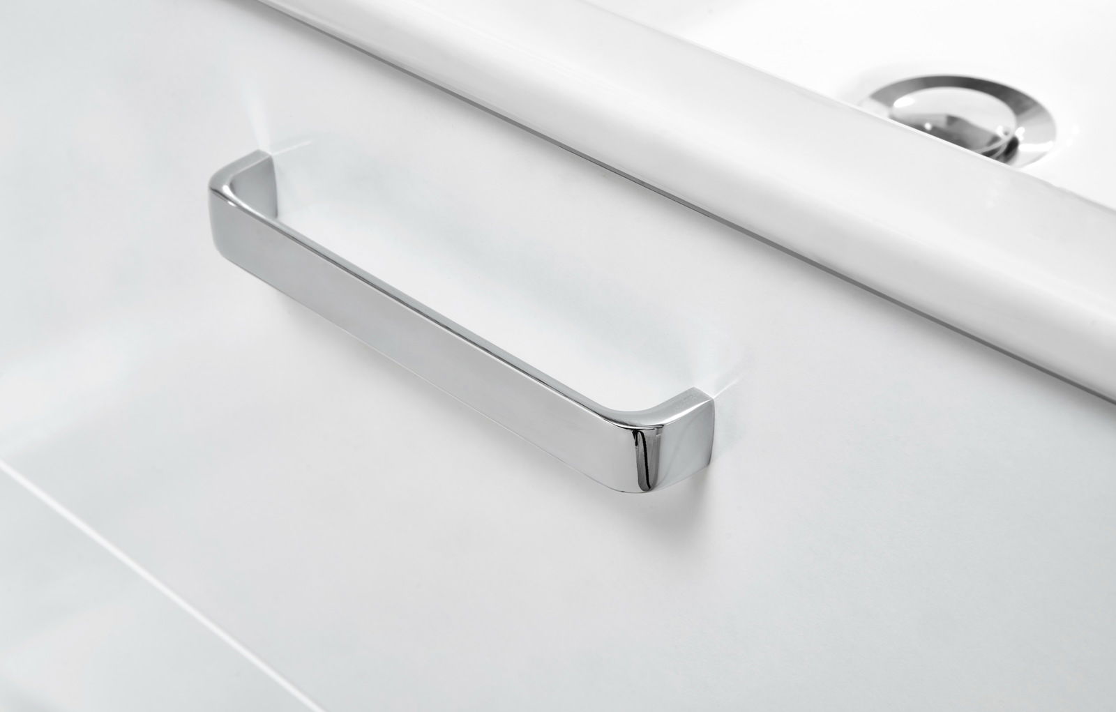 Nahaufnahme eines modernen, weißen Waschtischunterschranks mit einem glänzenden, chromfarbenen Griff.