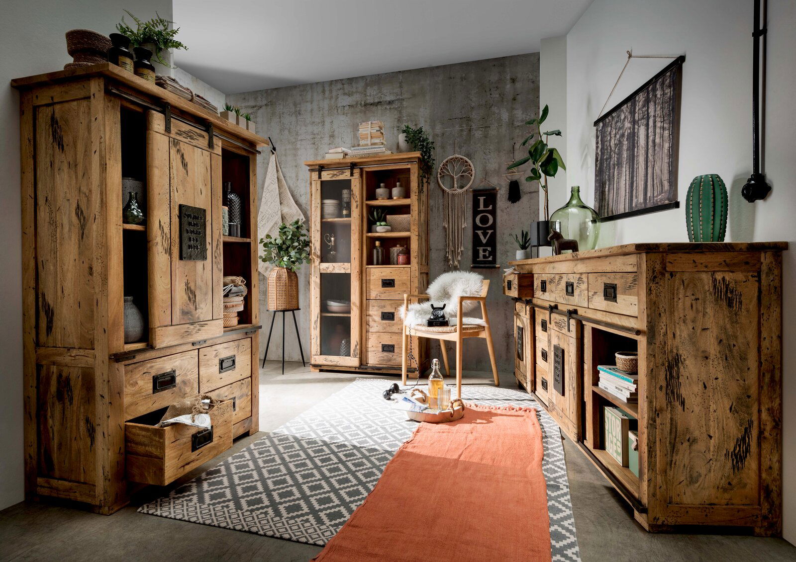 Rustikales Wohnzimmer mit Holzmöbeln, darunter eine Vitrine und ein Sideboard, aus der Perspektive von vorne rechts betrachtet.