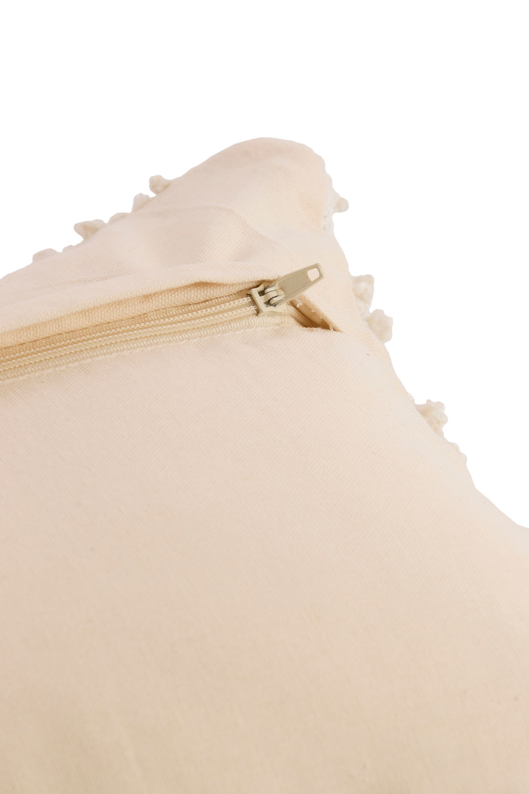 Nahaufnahme eines beigen Kissens mit Reißverschluss und dekorativen Bommeln an der Seite.