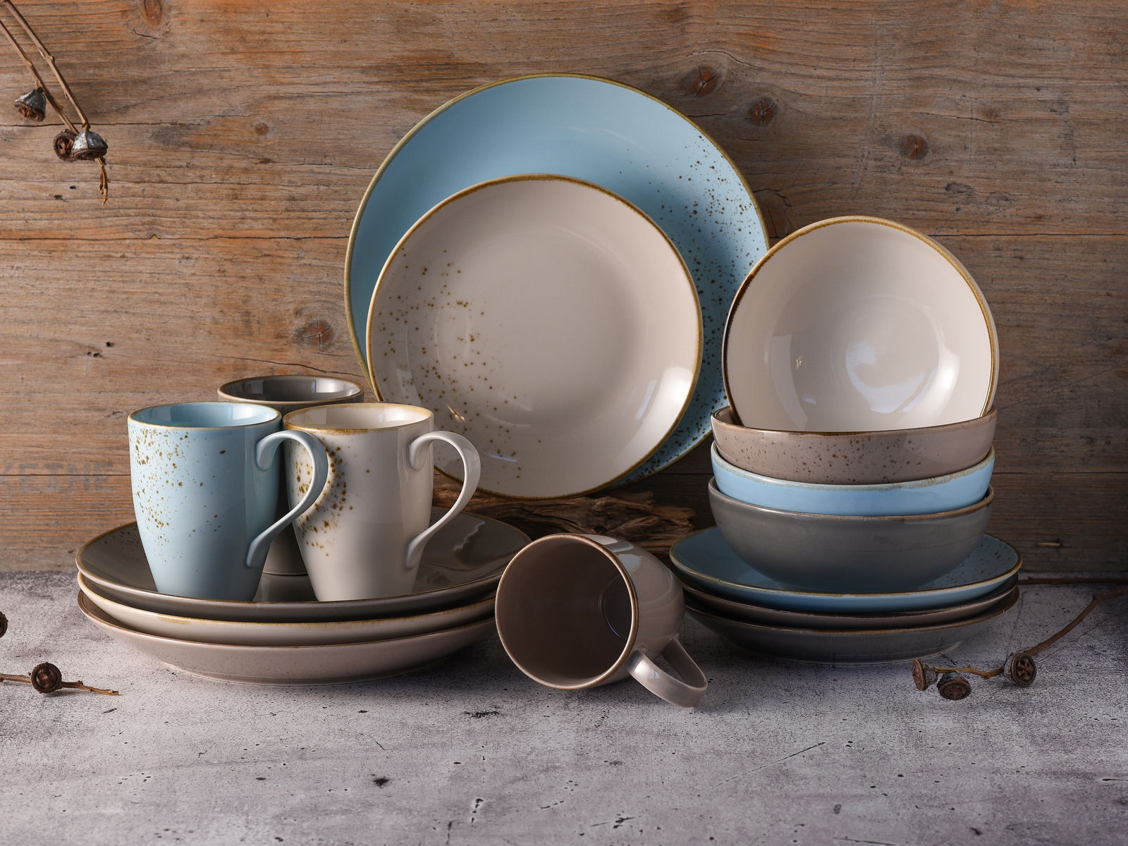 Kombiservice 16-tlg in sanften Blau- und Beigetönen, bestehend aus Tellern, Schalen und Tassen, auf rustikalem Hintergrund, seitliche Perspektive