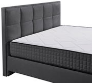 Graues Boxbett mit gestepptem Kopfteil und weißer Matratze, seitliche Perspektive