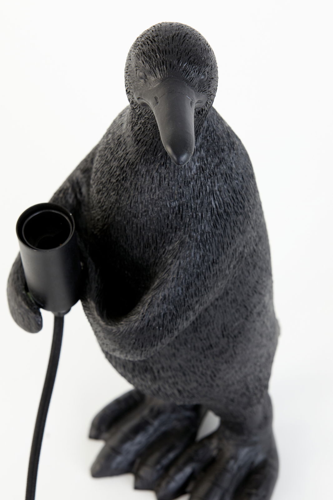 Pinguin-förmige Tischleuchte aus schwarzem Material, von oben fotografiert, mit einer Lampenfassung in der rechten Flosse.