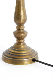 Nahaufnahme eines antik aussehenden, goldfarbenen Lampenfußes mit Kabelanschluss, seitliche Perspektive
