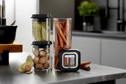 De PANTRY-set met voorraadpotten, bestaande uit twee stapelbare glazen potten gevuld met laurierblaadjes en nootmuskaat, en een hoge glazen pot met kaneelstokjes, gezien vanaf de zijkant op een keukenblad.