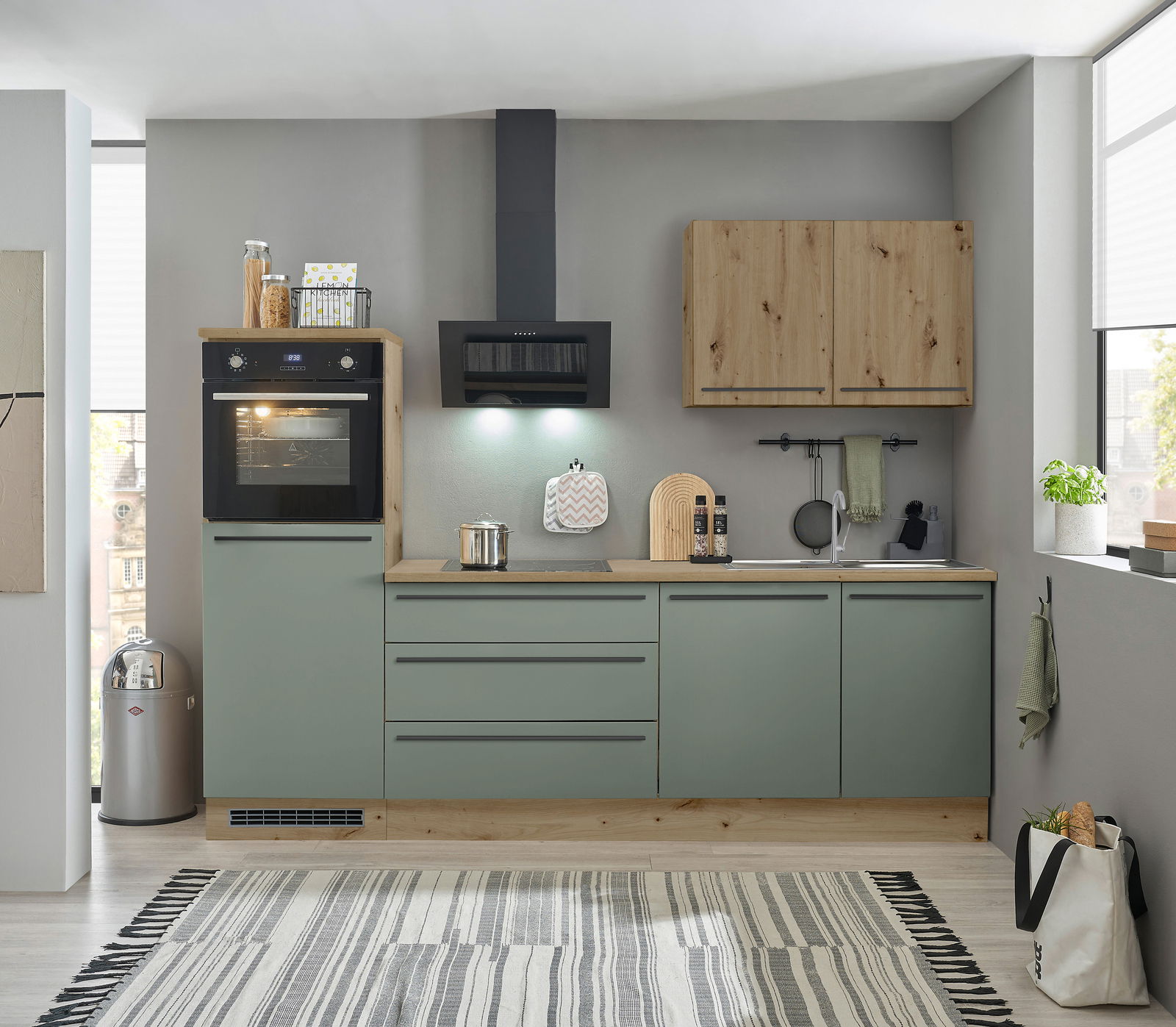 Moderne Küchenzeile in graugrün mit Holzakzenten, inklusive Backofen, Herd und Dunstabzugshaube, aus frontaler Perspektive.