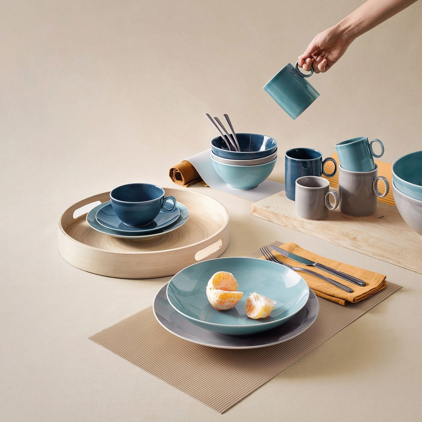 Kaffee-Obertasse in Dunkelblau auf einem gedeckten Tisch, von oben fotografiert, umgeben von Geschirr in verschiedenen Blautönen.