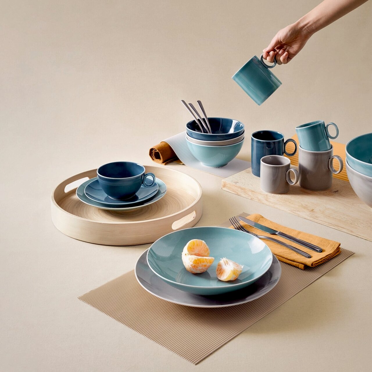 Kaffee-Obertasse in Dunkelblau auf einem gedeckten Tisch, von oben fotografiert, umgeben von Geschirr in verschiedenen Blautönen.