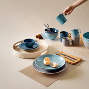 Kaffee-Obertasse in Dunkelblau auf einem gedeckten Tisch, von oben fotografiert, umgeben von Geschirr in verschiedenen Blautönen.