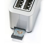 Nahaufnahme eines Toasters aus Edelstahl mit herausgezogener Krümelschublade, die Krümel enthält.