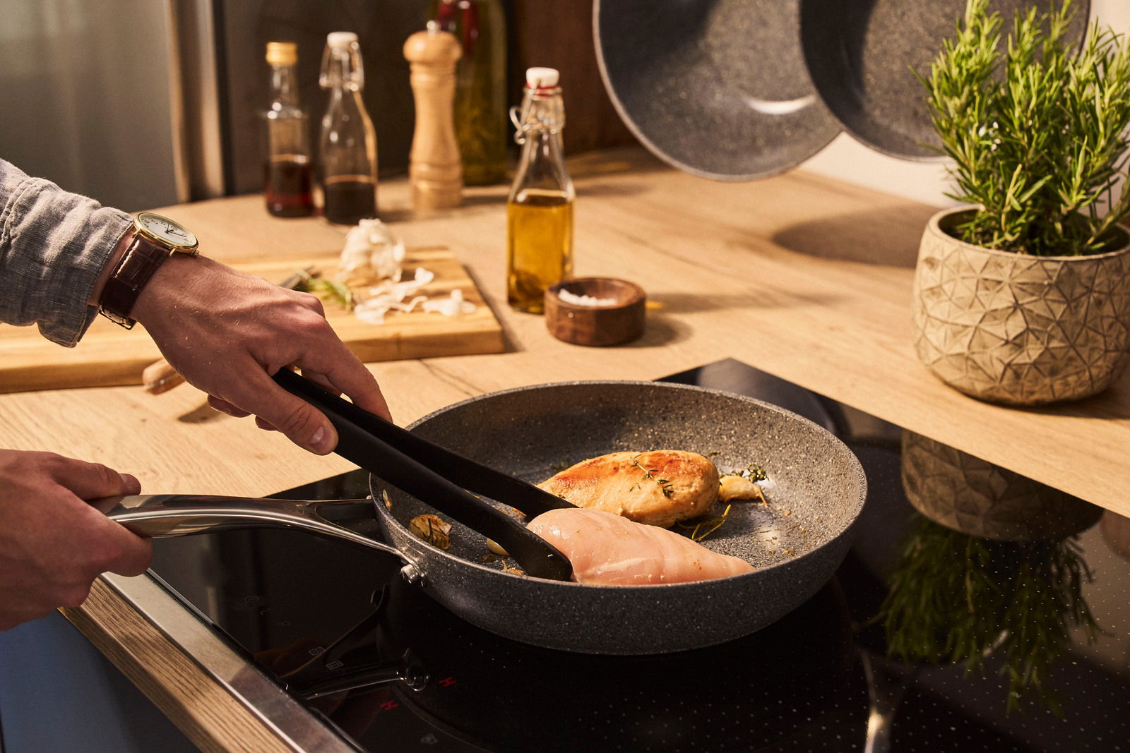 Bratpfanne mit 32 cm Durchmesser auf einem Herd, in der Hähnchenbrustfilets gebraten werden, seitliche Perspektive.