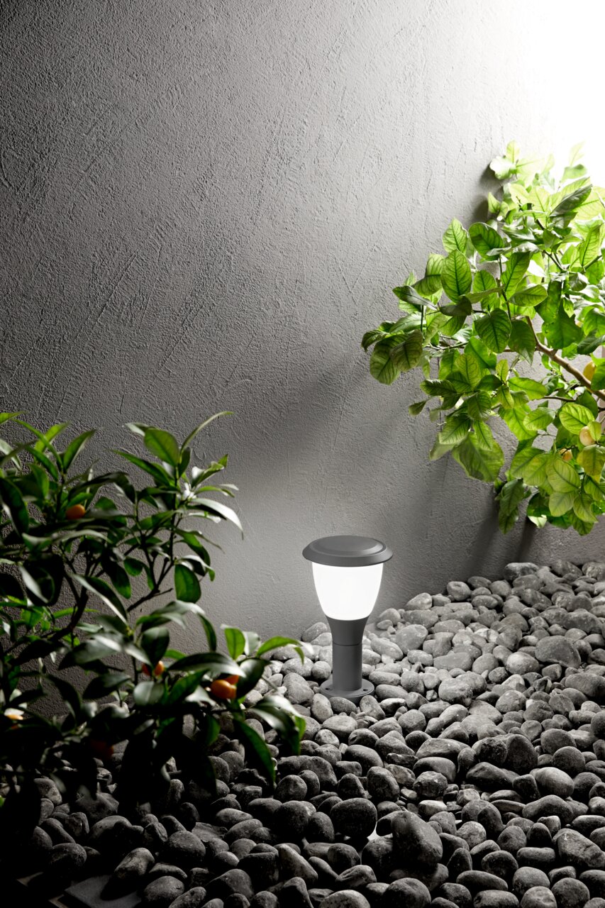 Moderne paallamp Fabas Luce THIAGO in een tuin met kiezelstenen en planten, zijaanzicht.