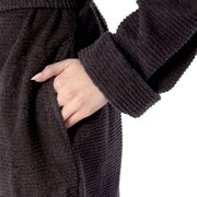 Nahaufnahme eines dunkelgrauen Kapuzenbademantels in Größe S, mit einer Hand in der Tasche.