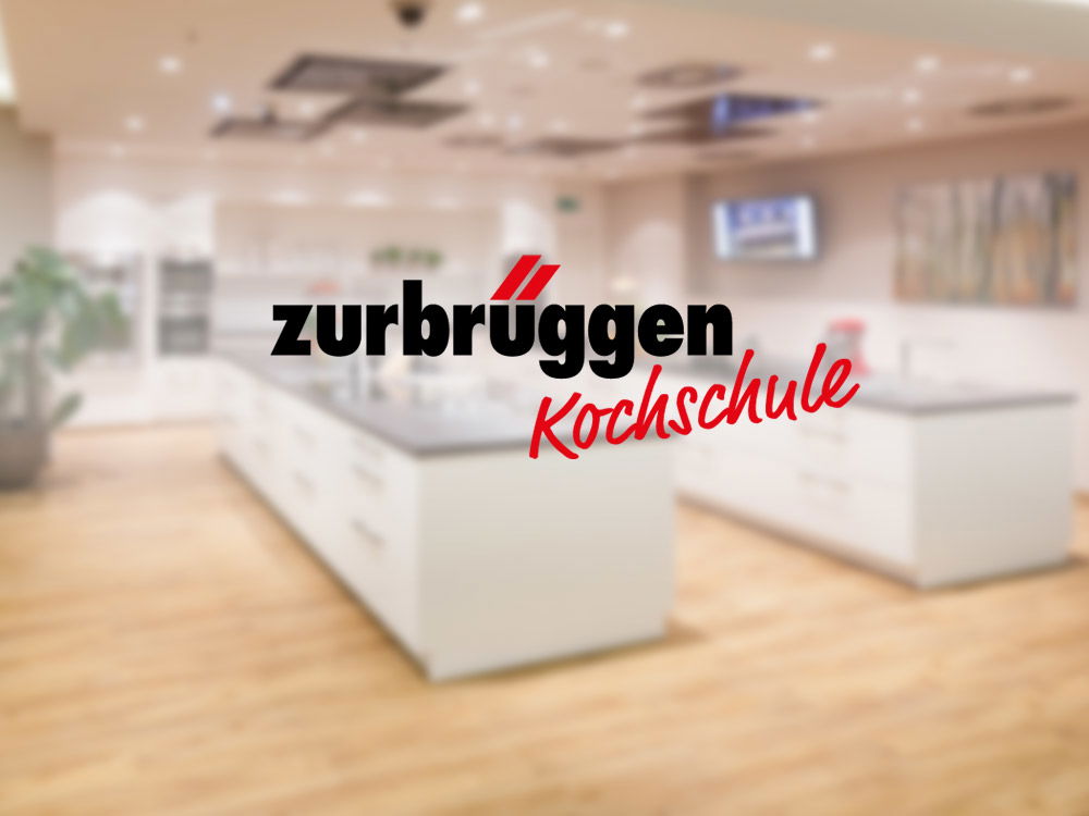 Moderne Showküche mit Kochinseln, darüber das Logo „Zurbrüggen Kochschule“ zentral eingeblendet