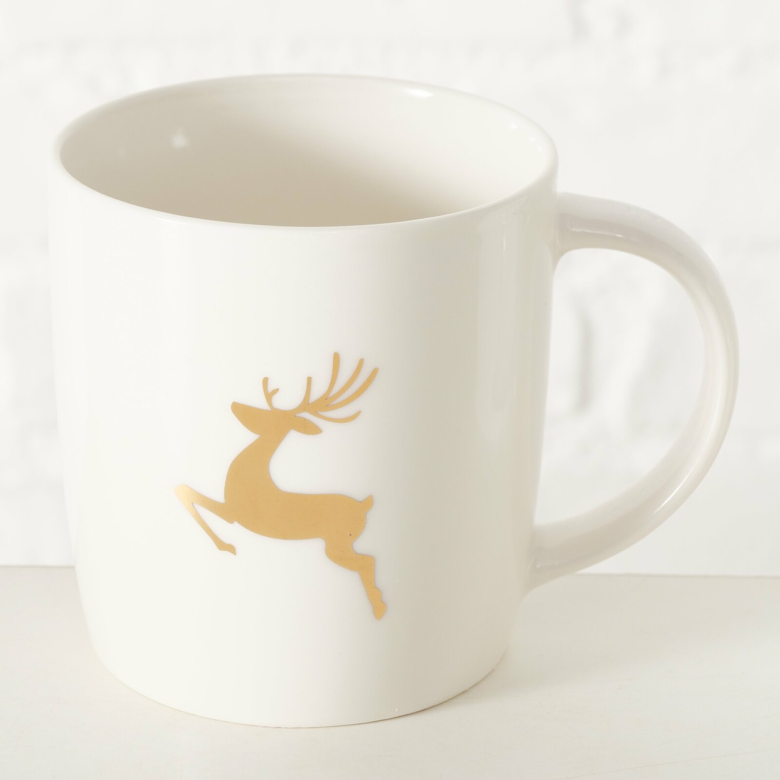Weißer Becher mit goldfarbenem Hirschmotiv, seitliche Perspektive