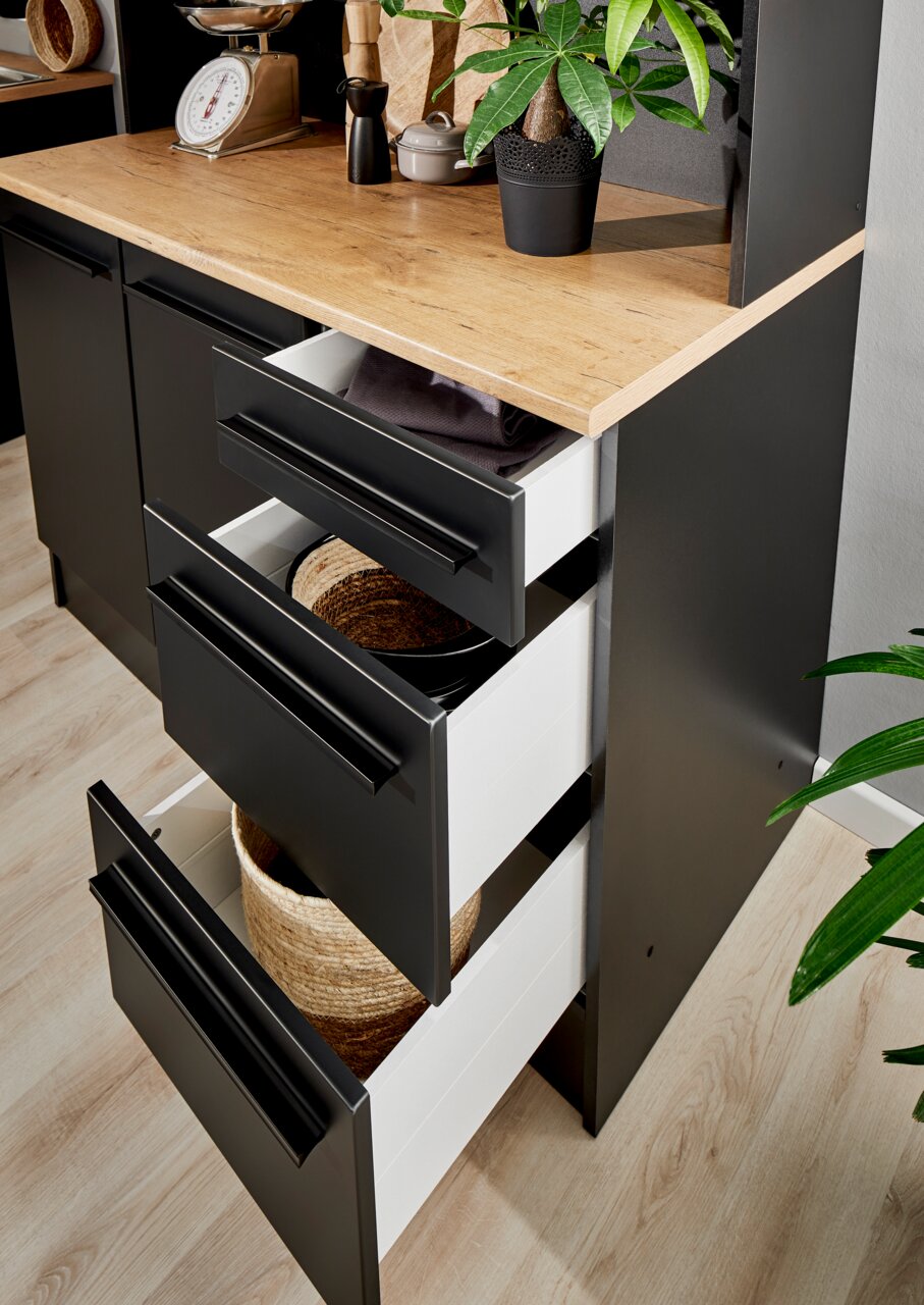 Nahaufnahme eines modernen Buffet-Schranks mit schwarzen Schubladen und einer Holzarbeitsplatte, von oben betrachtet.