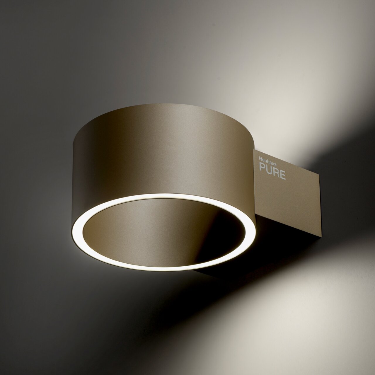 Moderne Wandleuchte PURE Clipse in seitlicher Perspektive mit rundem, goldfarbenem Gehäuse und leuchtendem LED-Ring.