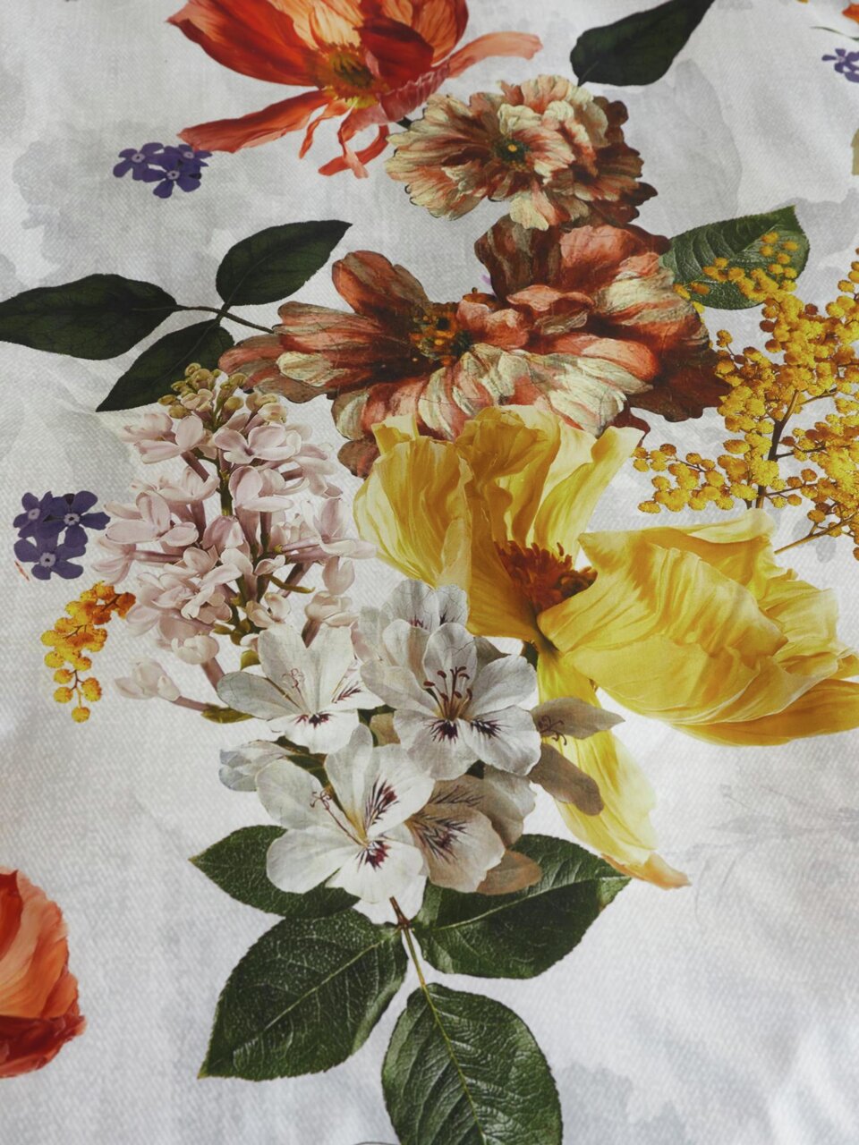 Nahaufnahme von Bettwäsche mit buntem Blumenmuster in verschiedenen Farben wie Rot, Gelb und Weiß auf weißem Hintergrund.