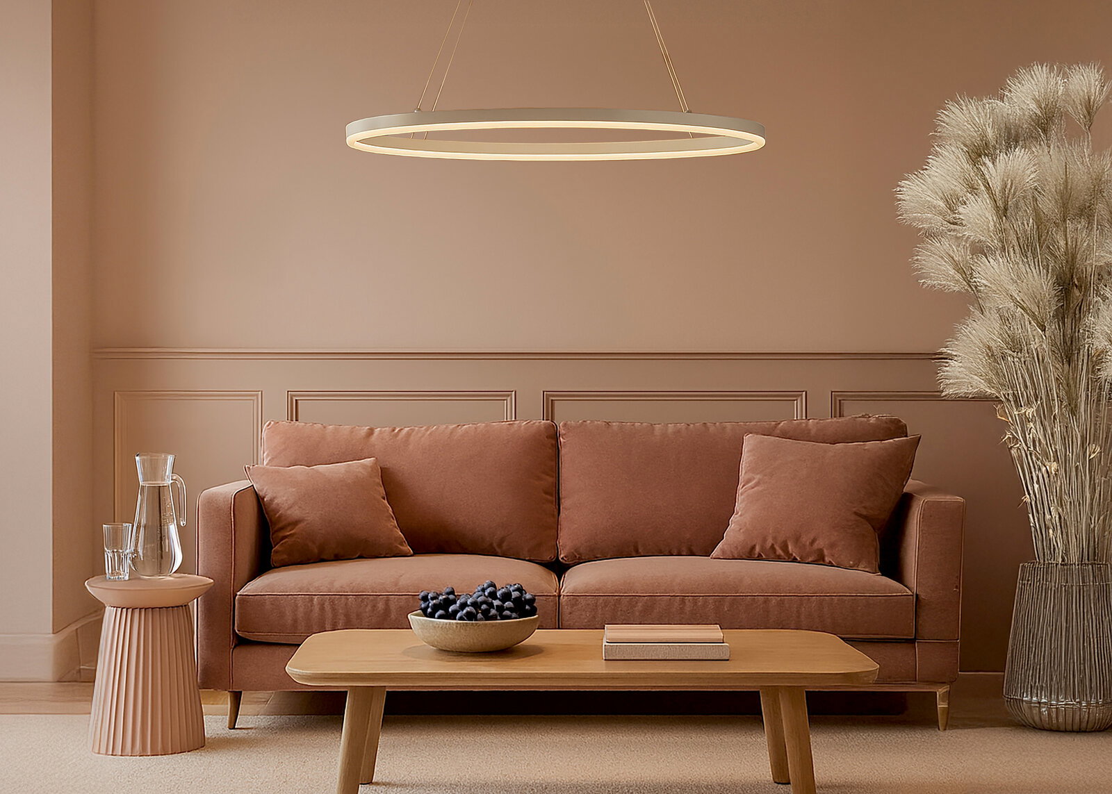 Moderne, ringförmige LED-Pendelleuchte in Weiß über einem braunen Sofa im warmen Wohnzimmerambiente, frontale Perspektive.