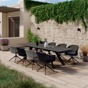 Een moderne tuintafel met zes stoelen op een terras, omringd door planten, gezien vanuit de zijkant.