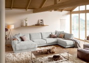 Gemütliche Rundecke in einem modernen Wohnzimmer mit Holzdecke und großen Fenstern, seitliche Perspektive.
