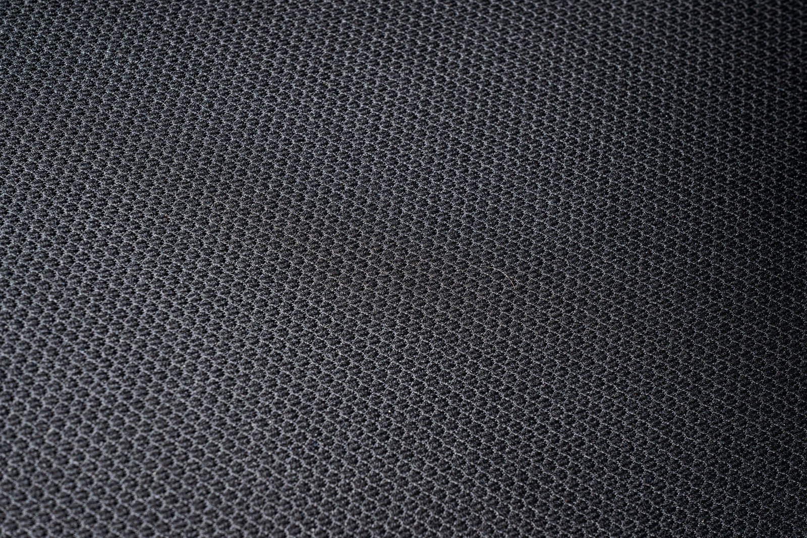 Nahaufnahme eines schwarzen, strukturierten Stoffes, vermutlich Sitzfläche eines Drehstuhls.