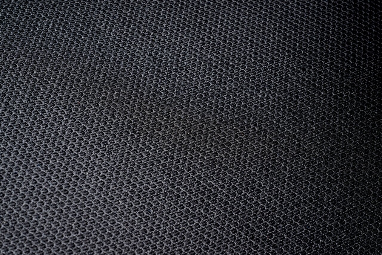 Nahaufnahme eines schwarzen, strukturierten Stoffes, vermutlich Sitzfläche eines Drehstuhls.