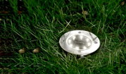 Runde Solarleuchte aus Metall, eingebettet in Gras, aus der Vogelperspektive fotografiert.