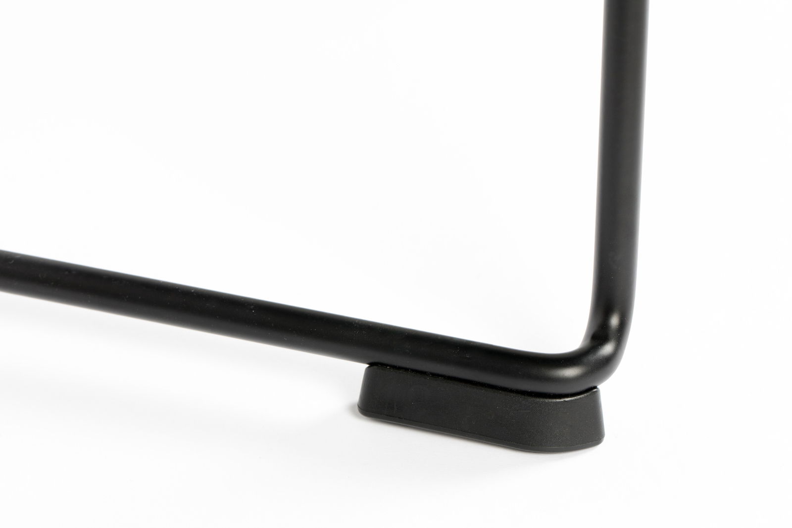 Nahaufnahme eines schwarzen Stuhlbeins mit abgerundeter Ecke und Kunststofffuß auf weißem Hintergrund