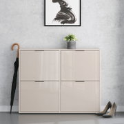 Beiges, hochglänzendes Schuhschrank-/Sideboard mit vier Klapptüren in Frontansicht, vor grauer Wand; oben steht ein kleiner Blumentopf, daneben ein Regenschirm und rechts ein Paar Pumps.