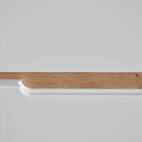 Detailansicht einer Kommode mit weißer Oberfläche und Holzleiste.