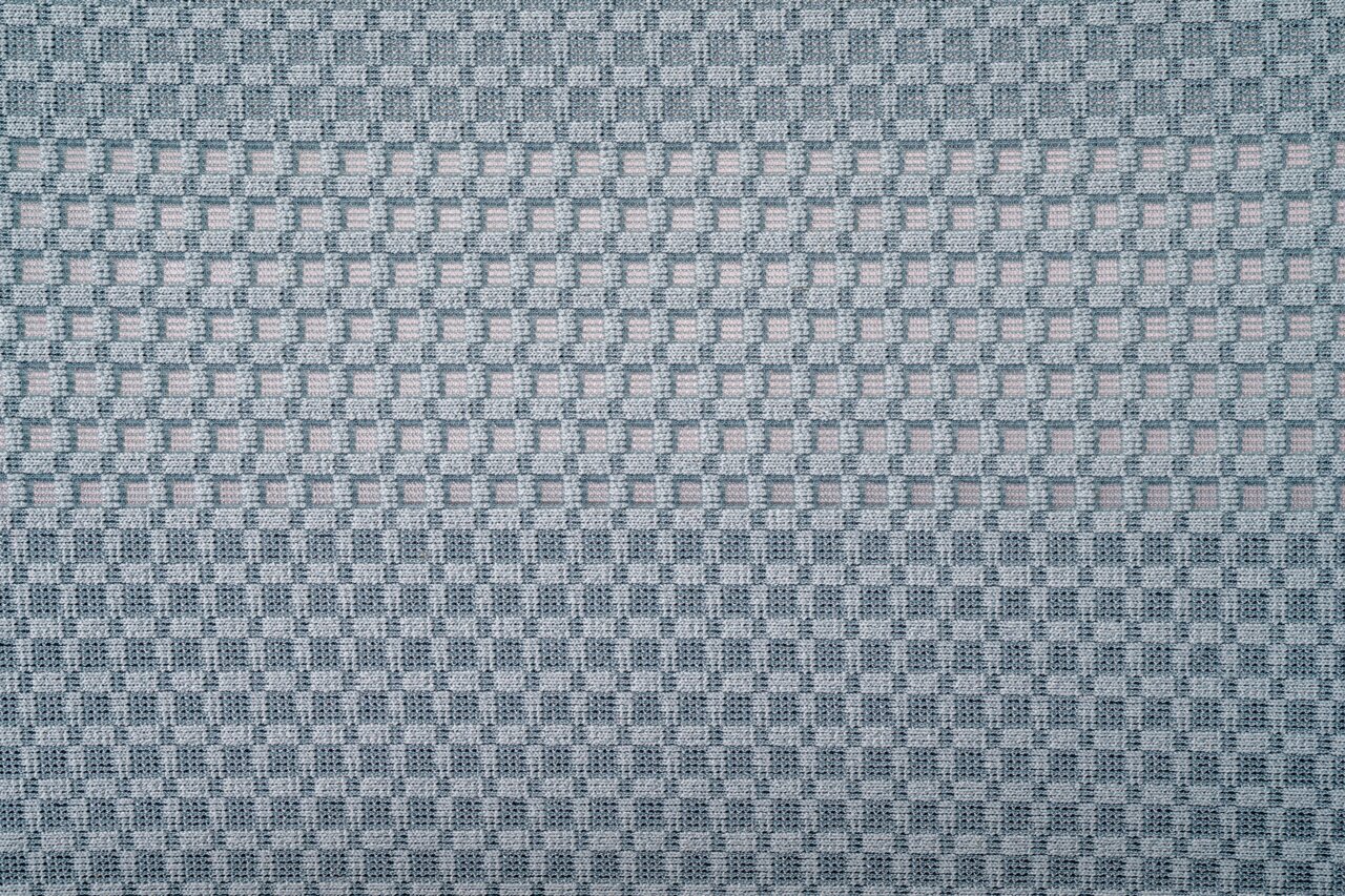 Nahaufnahme eines grauen Stoffmusters mit quadratischem Gitterdesign, Draufsicht