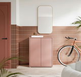 Moderner, niedriger Schuhschrank in Rosa mit zwei Türen, frontal fotografiert, in einem stilvoll eingerichteten Raum mit Spiegel und Fahrrad.