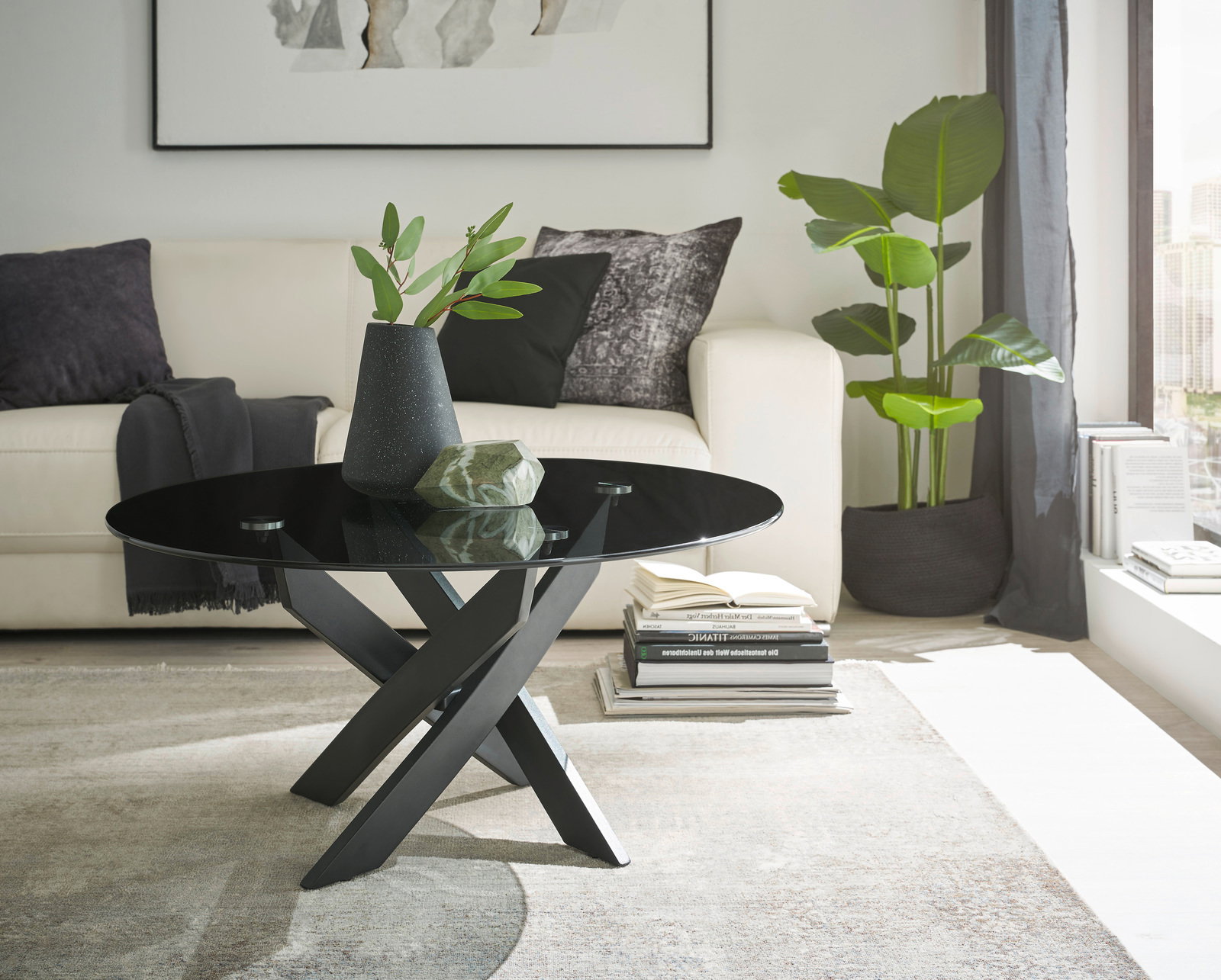 Moderner Couchtisch mit schwarzer Glasplatte und gekreuztem Metallgestell, seitliche Perspektive