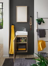 Modernes Gästebad mit Waschbecken und offenem Unterschrank, gefüllt mit Handtüchern und Pflegeprodukten, aus frontaler Perspektive.