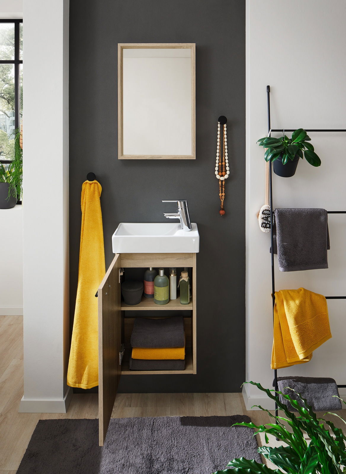 Modernes Gästebad mit Waschbecken und offenem Unterschrank, gefüllt mit Handtüchern und Pflegeprodukten, aus frontaler Perspektive.