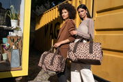 Zwei Frauen stehen vor einem gelben Container und halten Taschen mit Leopardenmuster. Die Taschen sind aus der Perspektive von vorne zu sehen.