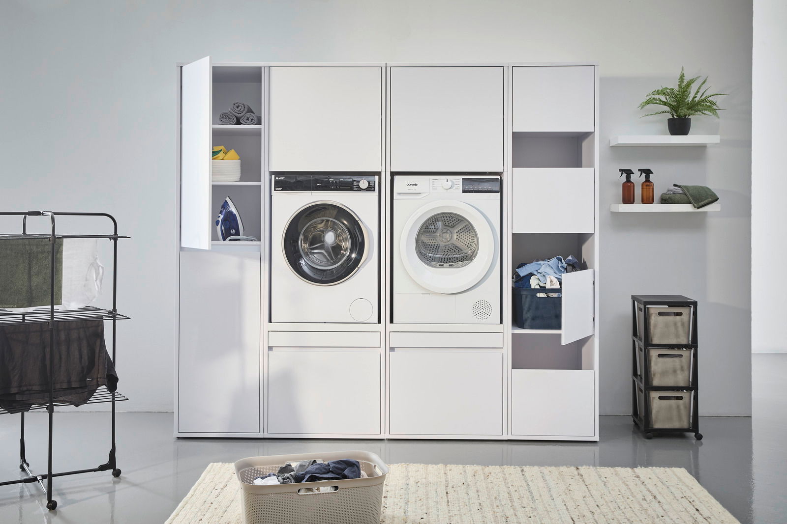 Frontale Ansicht eines modernen Hochschranksystems mit integrierter Waschmaschine und Trockner, umgeben von Stauraum für Wäsche und Reinigungsmittel.