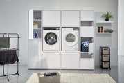 Frontale Ansicht eines modernen Hochschranksystems mit integrierter Waschmaschine und Trockner, umgeben von Stauraum für Wäsche und Reinigungsmittel.