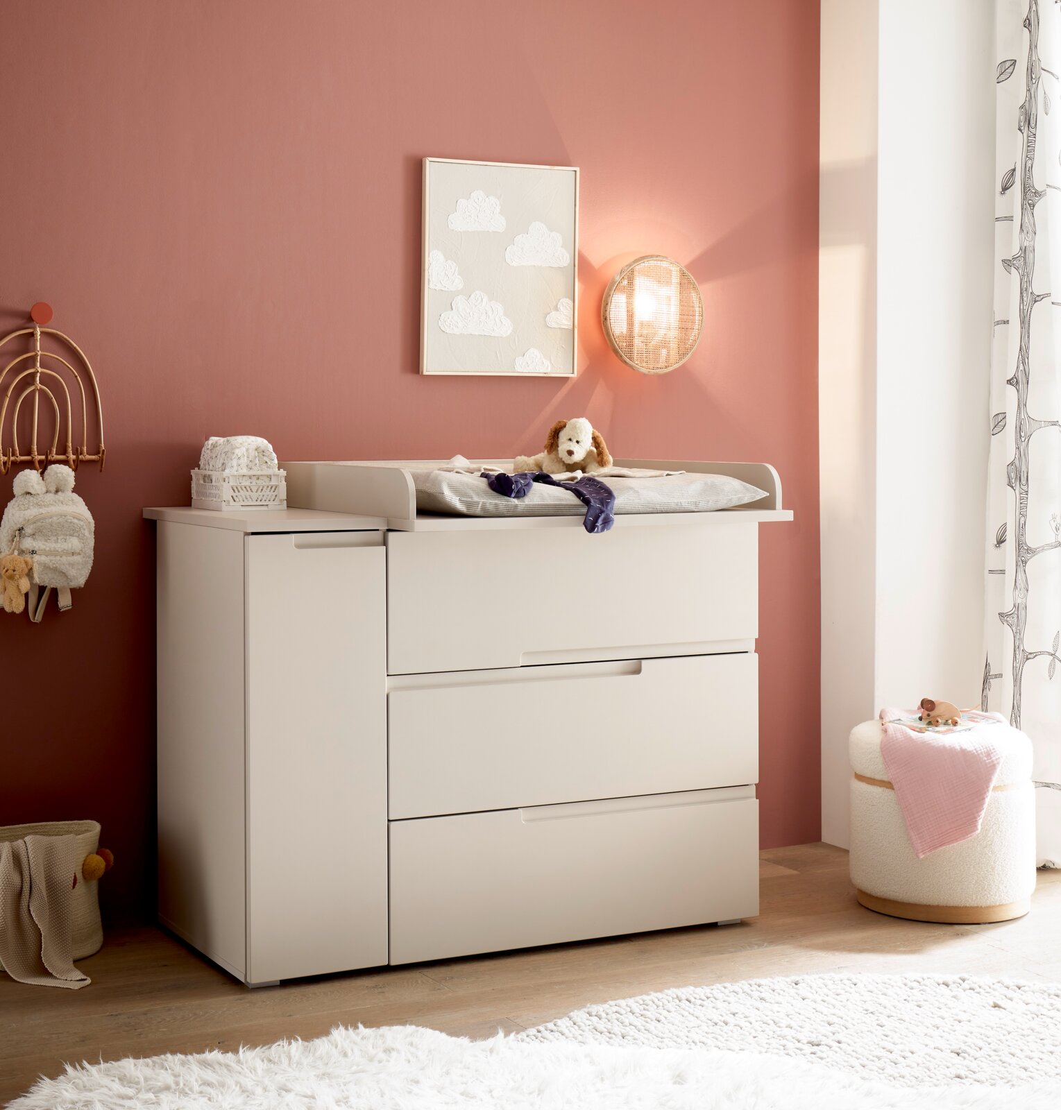 MyBaby Wickelkommode SPICE/PEPPINI Weiße Baby-Wickelkommode mit Wickelaufsatz und Schubladen im Kinderzimmer vor rosafarbener Wand, seitliche Perspektive von vorn rechts.
