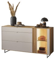 Modernes Sideboard aus Holz mit weißer Front und beleuchtetem Vitrinenfach, dekoriert mit Vase, Büchern und Tischlampe, in Frontansicht leicht von rechts.