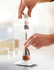 Eierköpfer mit Salzstreuer in Aktion, seitliche Perspektive auf einem Tisch.