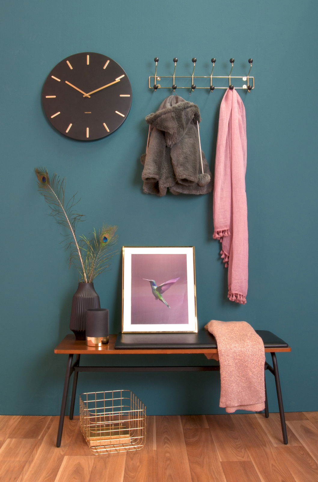 Garderobe gold XL an einer blauen Wand, frontal fotografiert, mit Jacken und Schal behängt, daneben eine Uhr und Dekoration auf einer Bank.