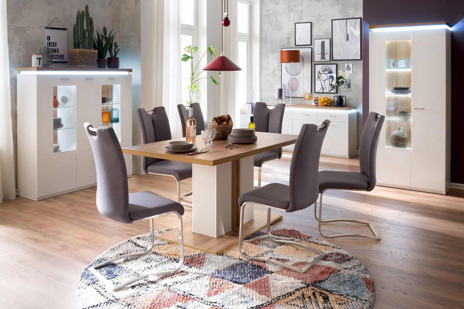 Esszimmer mit modernem Esstisch und sechs Stühlen, umgeben von stilvollen Vitrinen und Sideboards, aus der Perspektive des Raumes fotografiert.